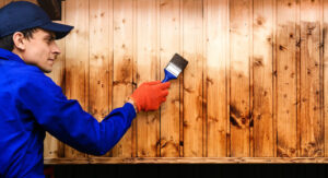 Fence Painting. Contractor Worker Paint With Brush A Wood fence.