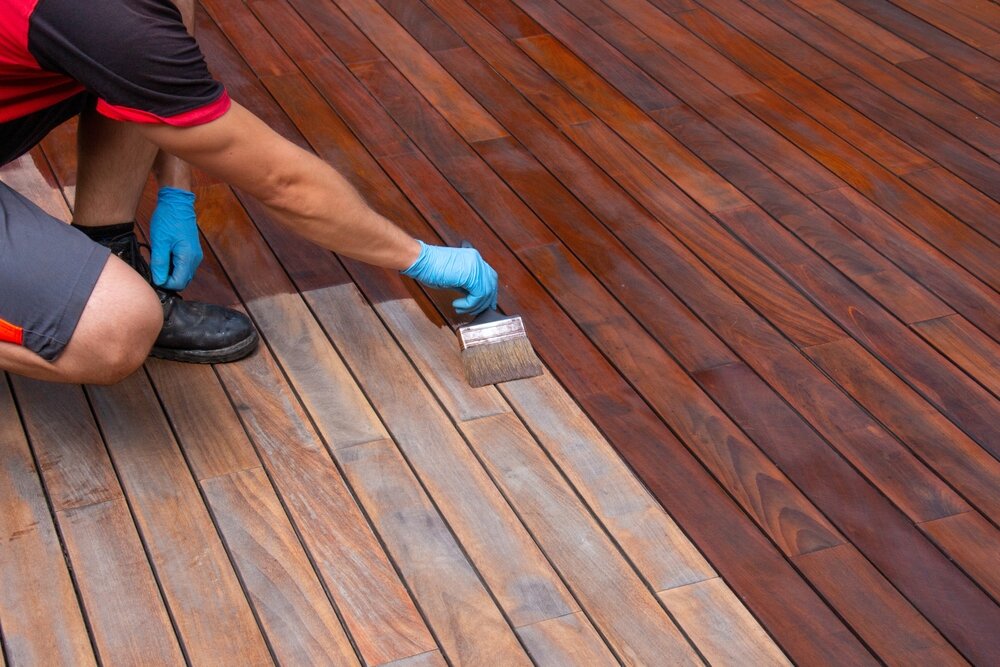 Deck Painting. Worker Applying paint With A Brush Wood Decking Renovation.