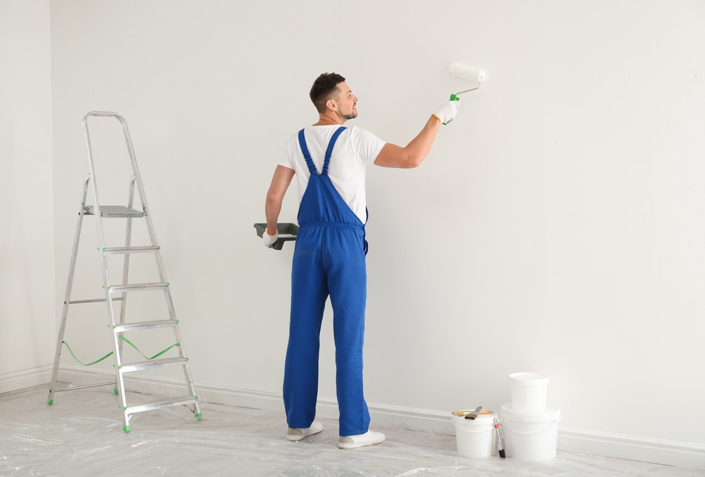 Exceptional Painting in Victoria, BC. Man painting wall with white dye indoors.