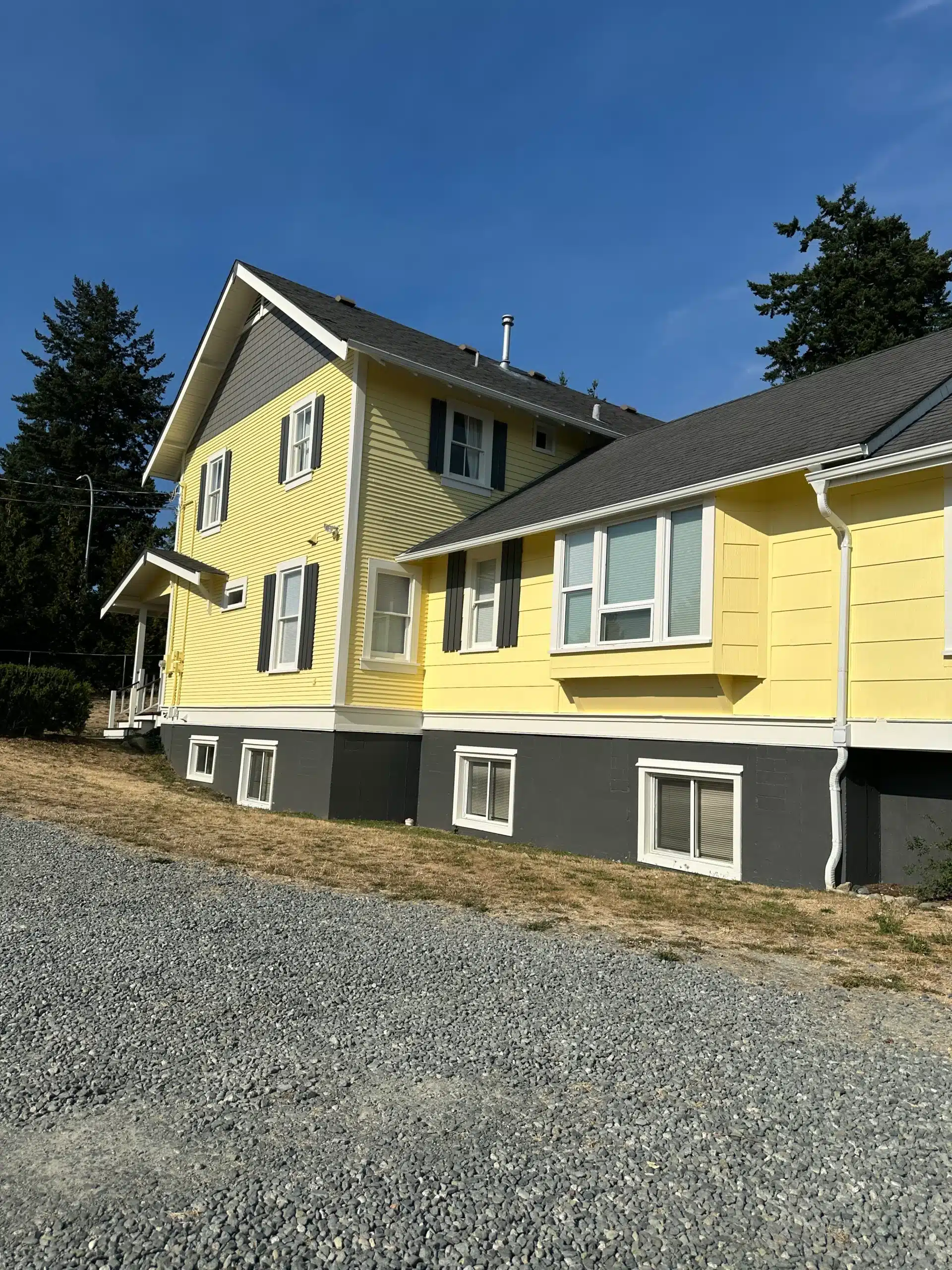 Yellow and Charcoal Exterior House Painting White residential exterior with dark trim in Greater Victoria