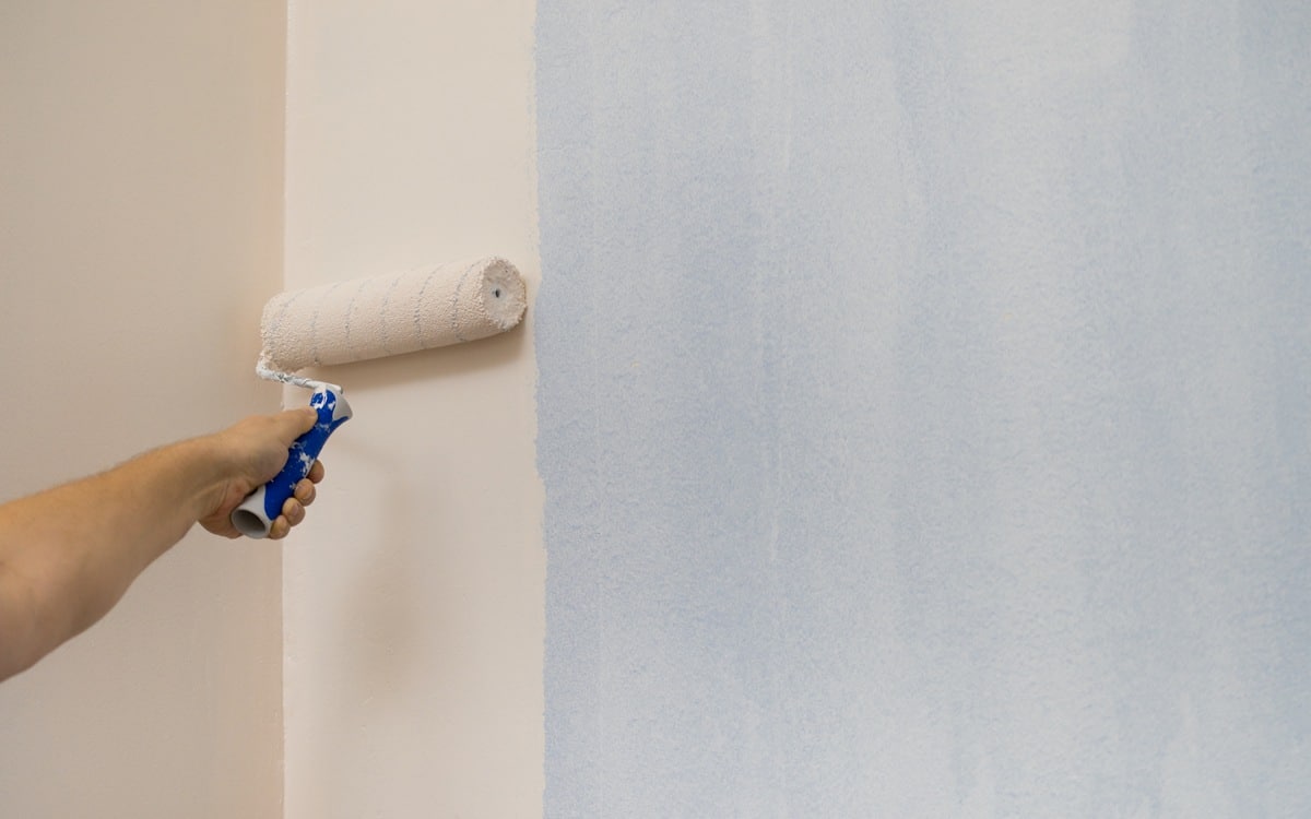Person applying paint on wall