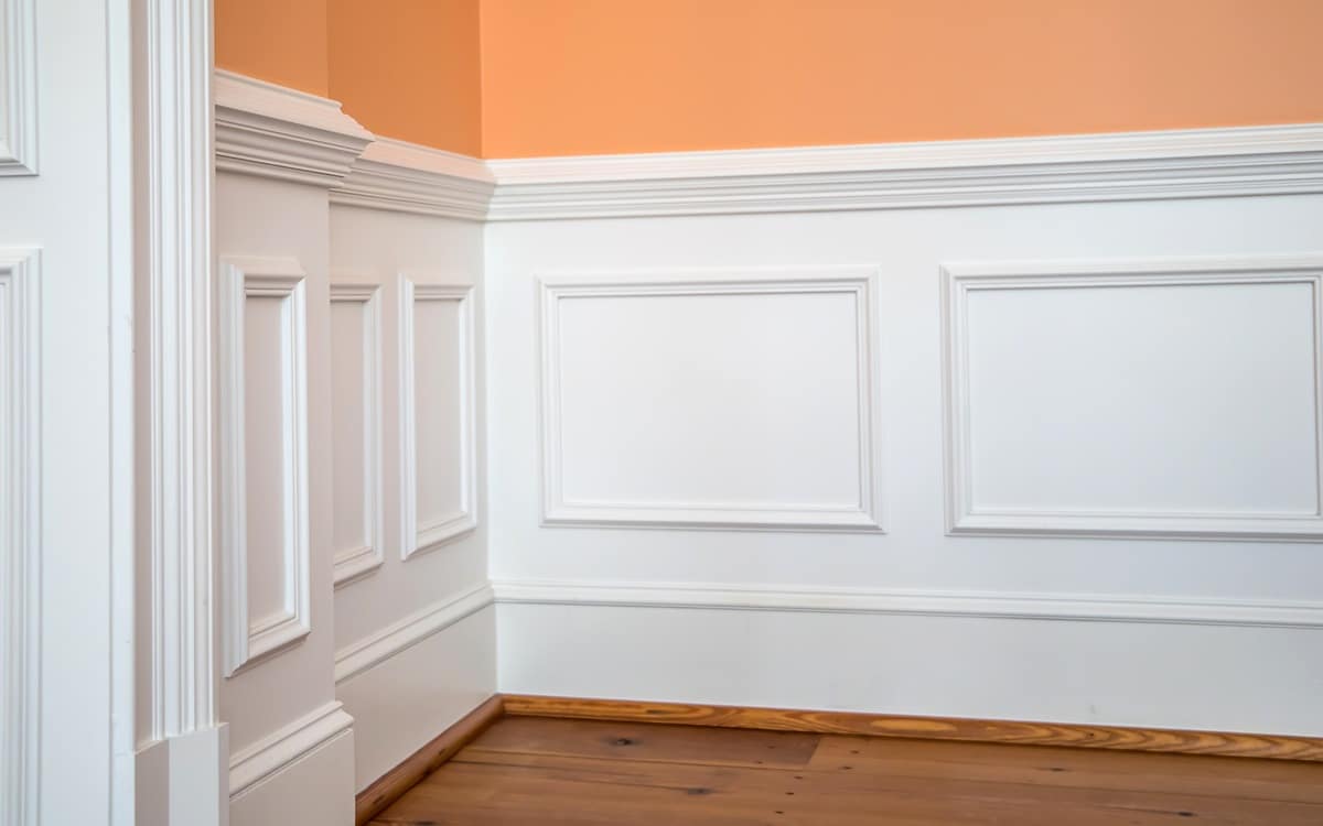 white wainscoting and chair rail on wall of orange peach dining living room of home house